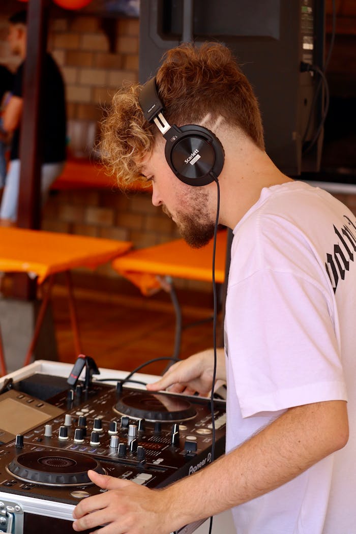 A young male DJ focused on mixing music during an outdoor event.