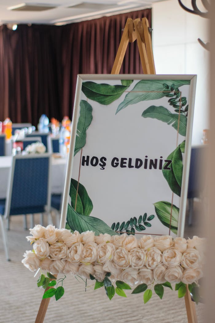 Welcome sign on easel with floral garland at an indoor event, featuring elegant decor.